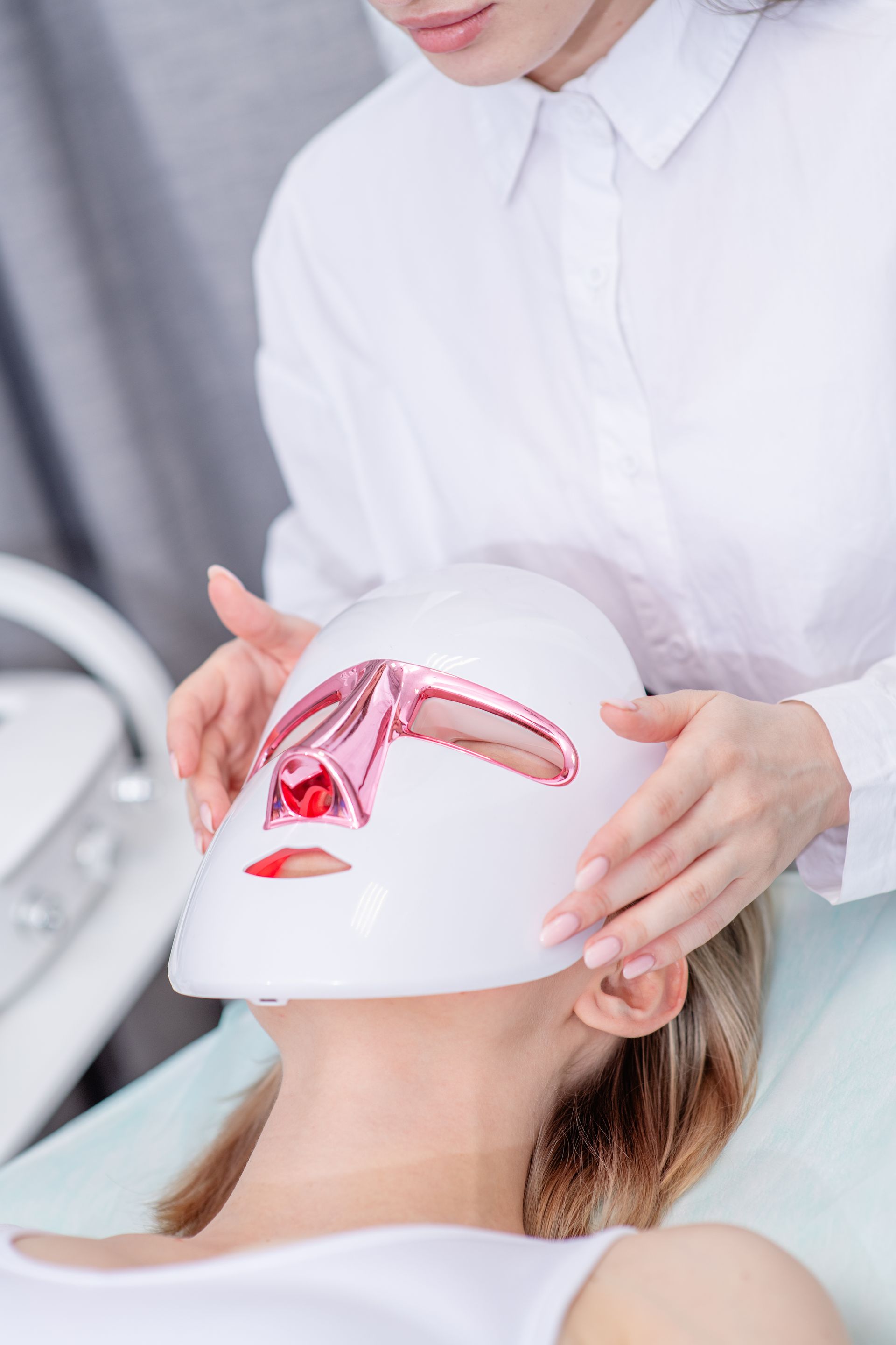A woman is getting a light therapy mask on her face.