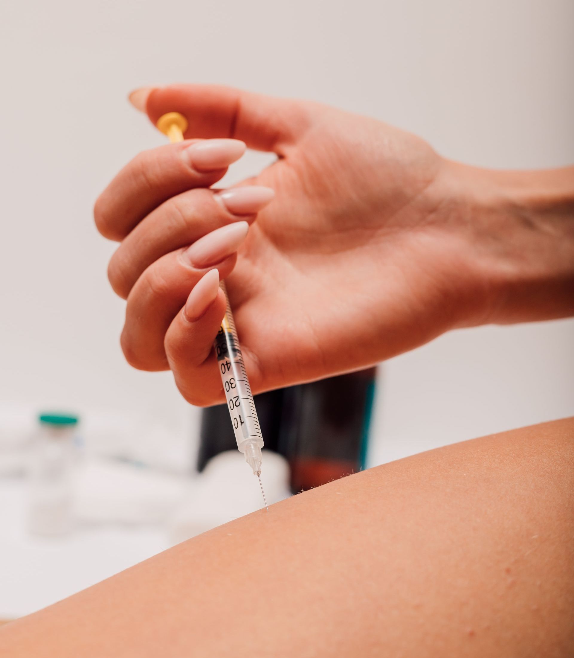A woman is getting an injection in her arm with a syringe