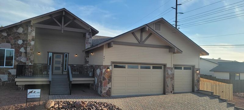 Modern suburban house exterior with two garage doors and a front porch under a clear sky