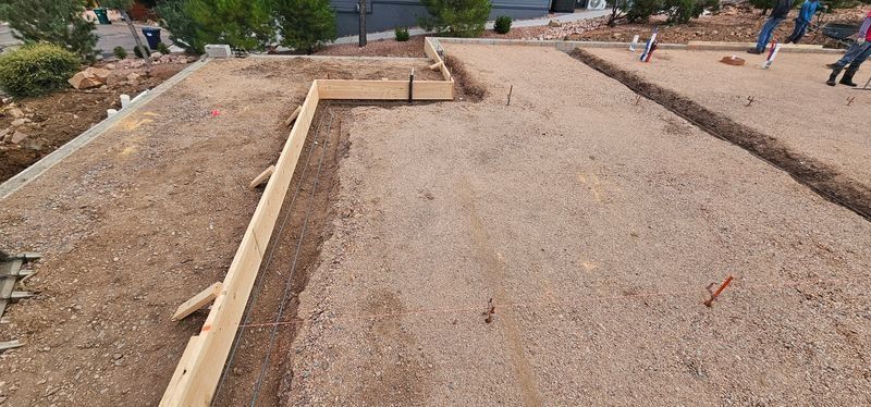 Construction site with wooden forms laid out on a gravel foundation area