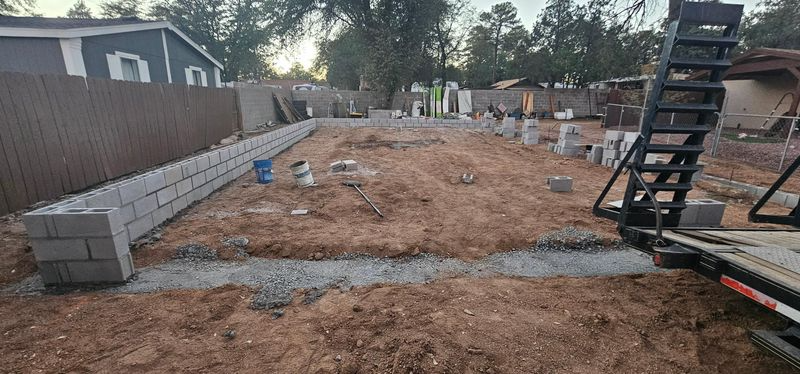Residential construction site with dirt foundation, cinder blocks, and a staircase on the right