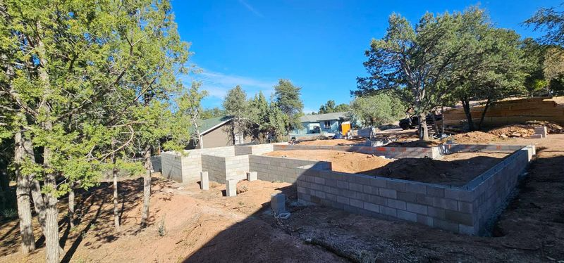 Outdoor yard with stone retaining walls, trees, and a clear blue sky