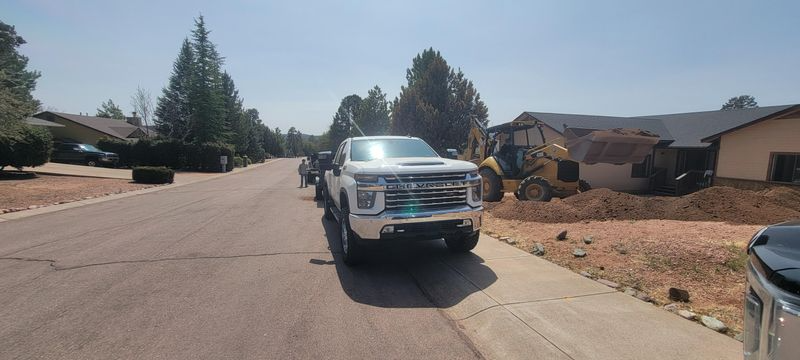 Silver pickup truck parked on a sunny suburban street near houses and dirt lots