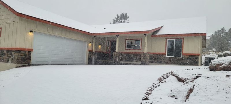 Snow-covered suburban house with a stone facade and garage during a snowy day