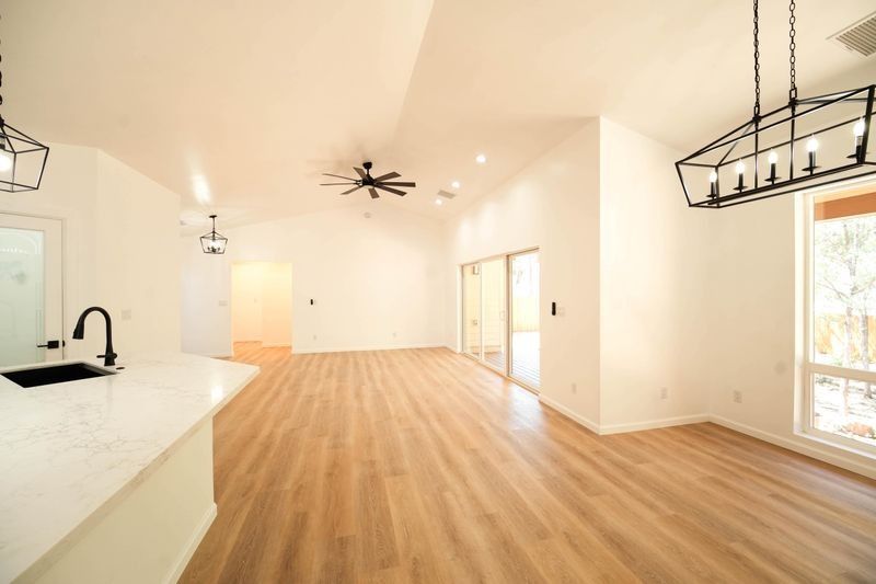 Bright open living room with wood floors, white walls, and large windows.