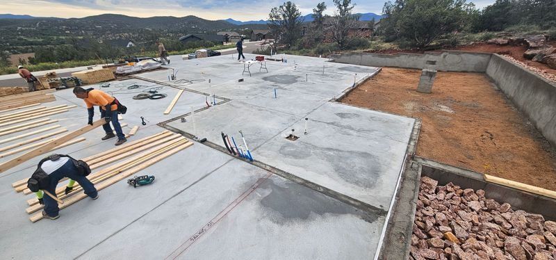 Workers installing roofing membrane on a flat roof at a construction site, with mountains in the background