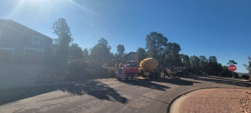 Roadwork truck and cement mixer on a sunny residential street with traffic cones and stop sign