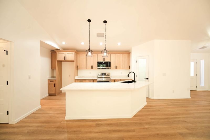 Bright open kitchen with white island, wood floors, and pendant lights in a modern home