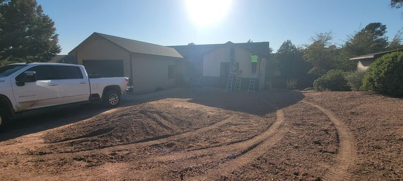 White pickup truck beside a house with a large dirt driveway under bright sun