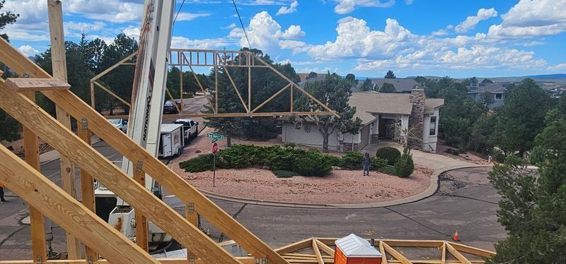 Wooden coaster track overlooking a landscaped theme park with buildings and blue sky