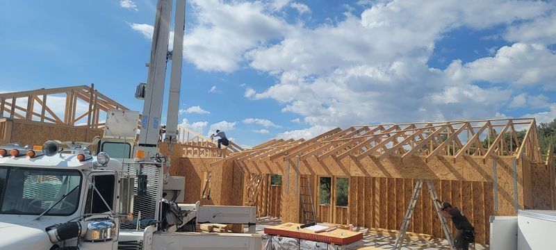 Construction site with wooden house framing and a crane under a blue sky
