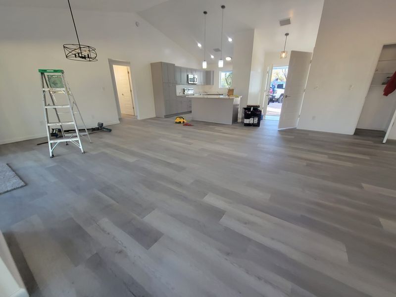 Empty modern room with gray flooring, white walls, and a step ladder near the left wall