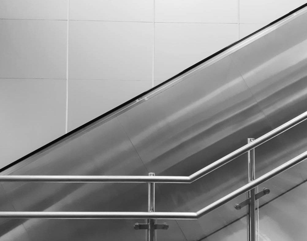 Black and White Image of an Escalator With Steel Handrails Against a Tiled Wall — Highlander Metals in Parramatta, NSW