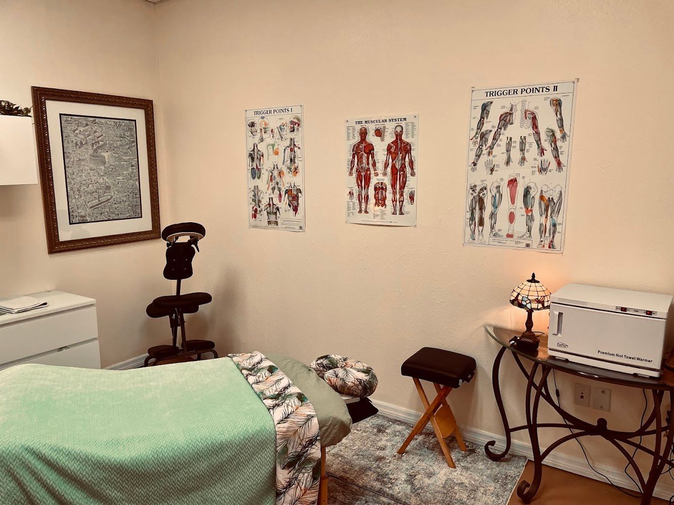 A massage table with a green blanket laid over it.
