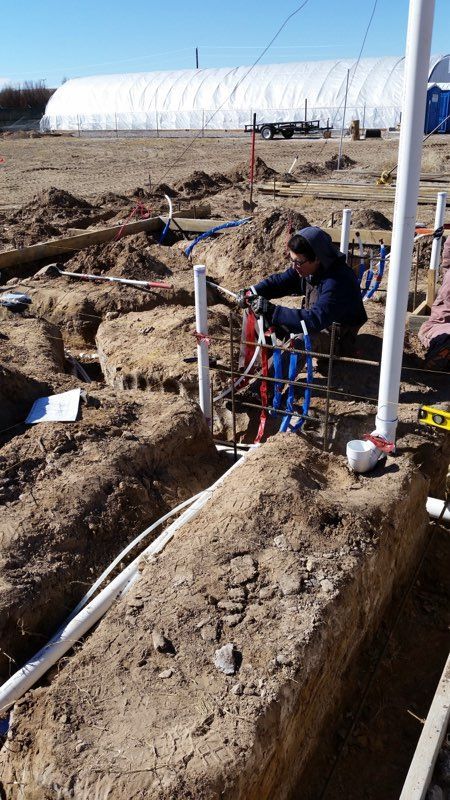 A man is working on a pipe in the dirt.