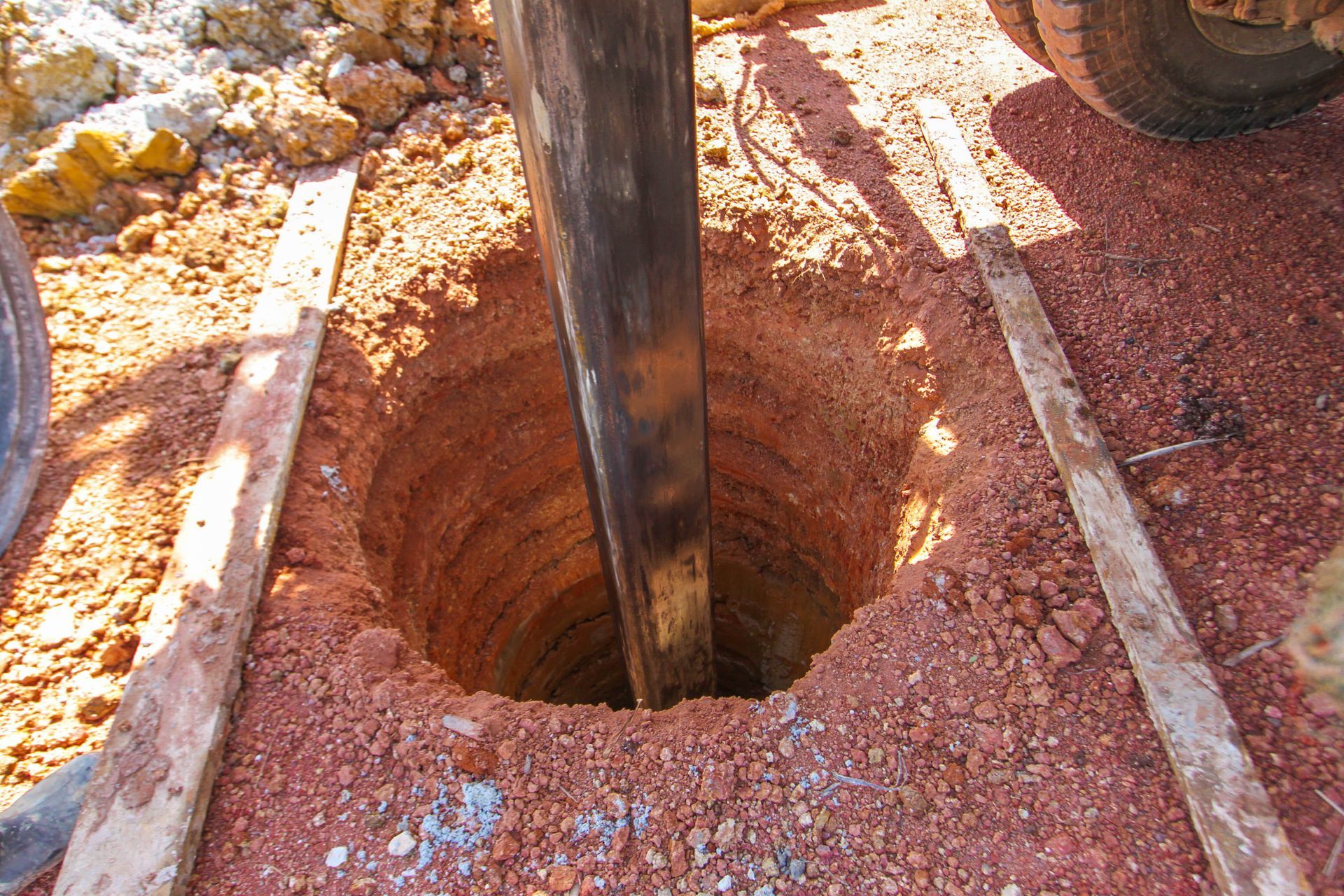 A hole in the ground with a pipe protruding from it for drilling work.