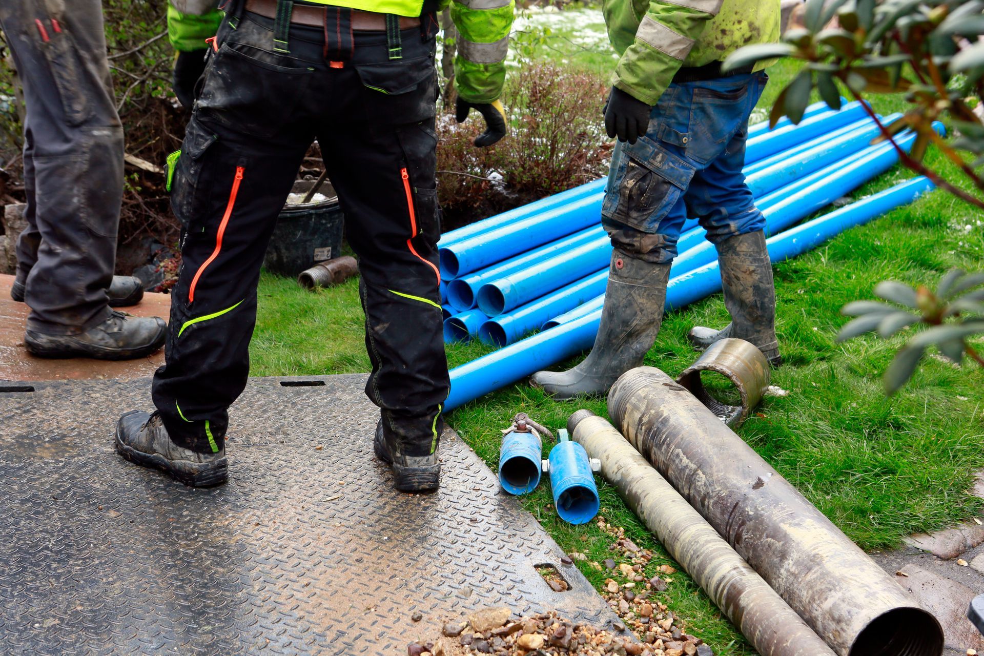 Three specialists drilling a deep well in the garden of a residential house.