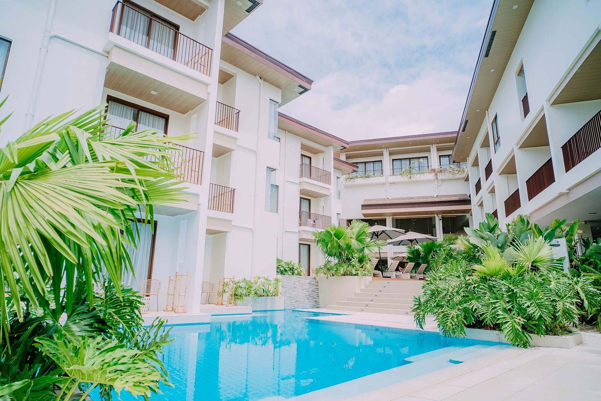 Modern apartment courtyard with a turquoise pool and lush tropical plants