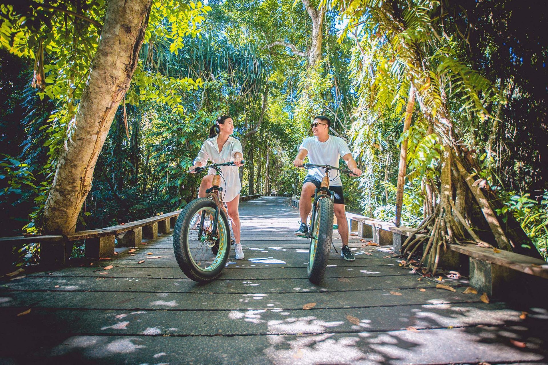 Couple riding fat tire bikes on a jungle boardwalk trail in El Nido