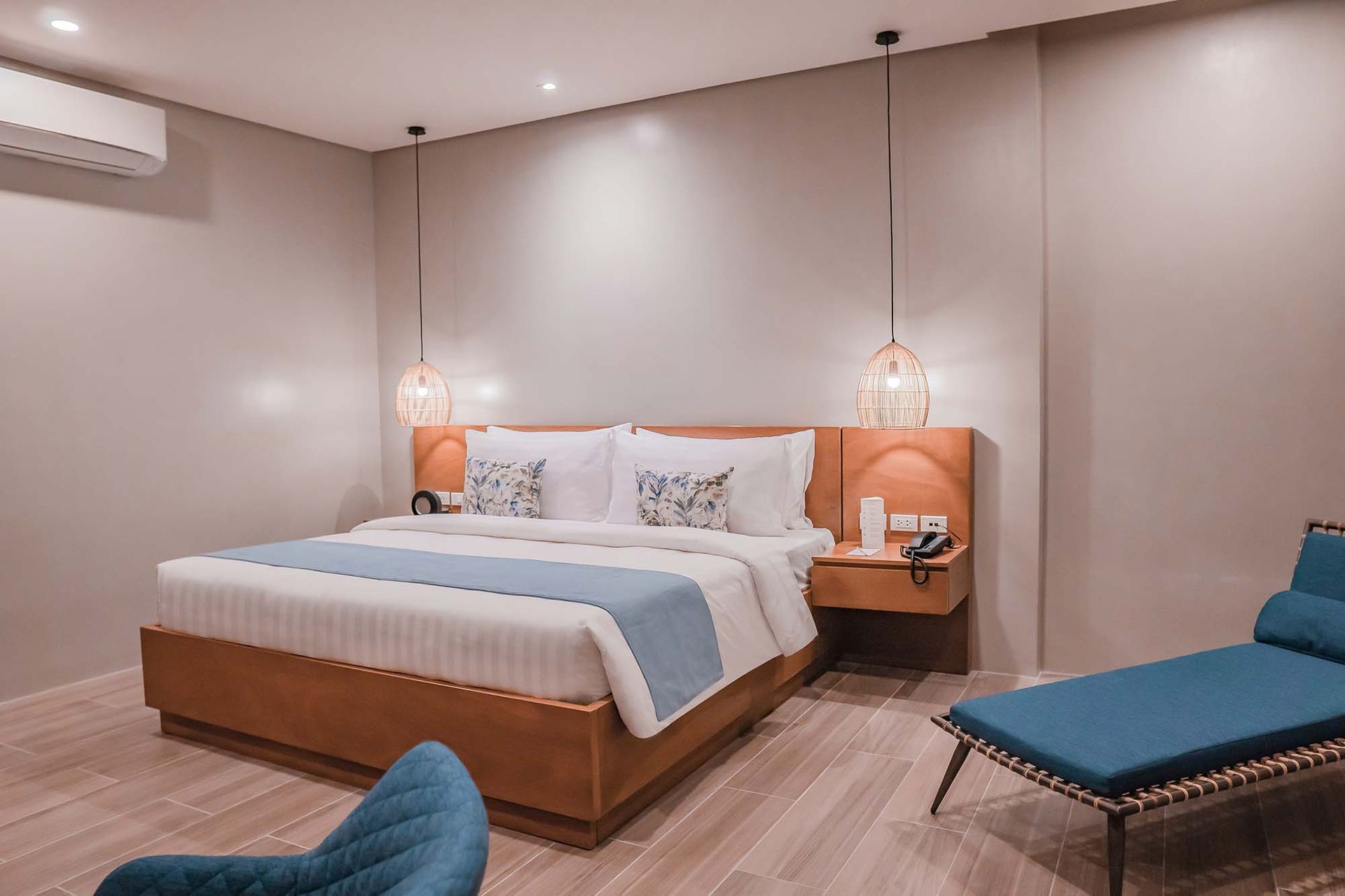 Deluxe room with comfortable king bed, blue runner, rattan pendant lamps, and matching blue lounge furniture