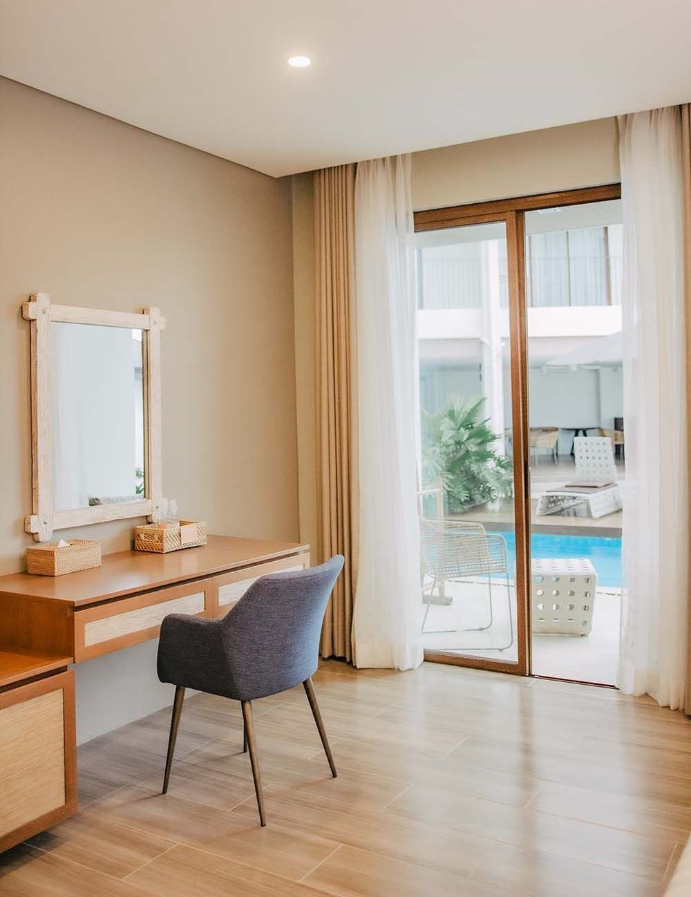 Bedroom with a desk, chair, mirror, and a glass door leading to a pool area.