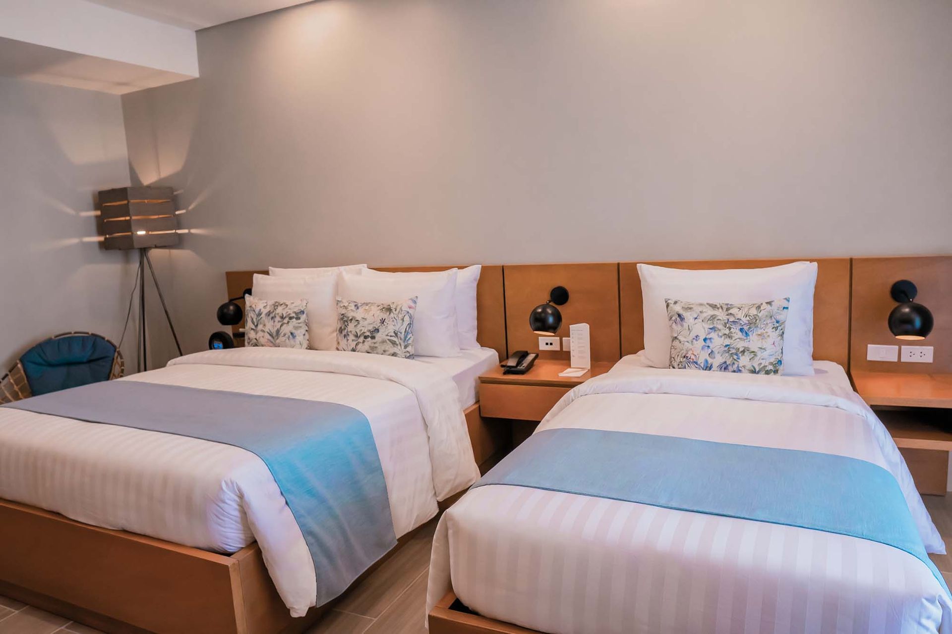 Twin beds in a modern hotel room with gray walls and blue-striped bedding.