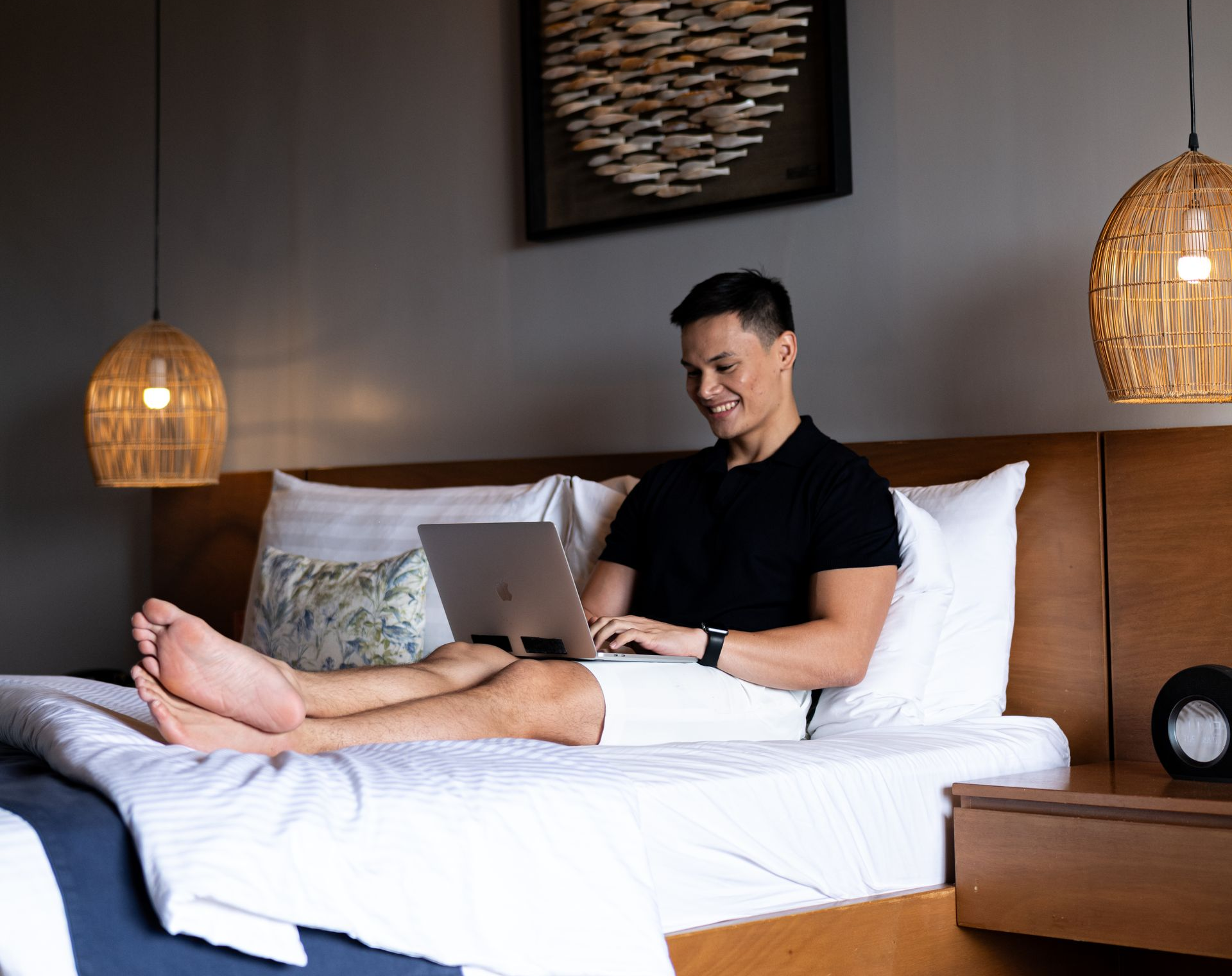 Guest working on a laptop from bed in a Charlie's El Nido guestroom