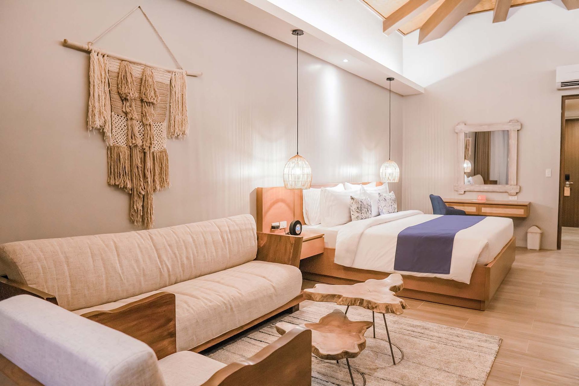 Premier room with queen bed, purple runner, comfortable beige sofa, natural wood accent tables and vanity area