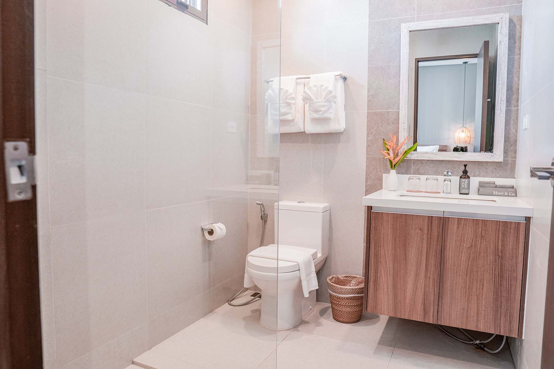 Modern bathroom with white tiled walls, wooden vanity cabinet, and neatly folded towels.