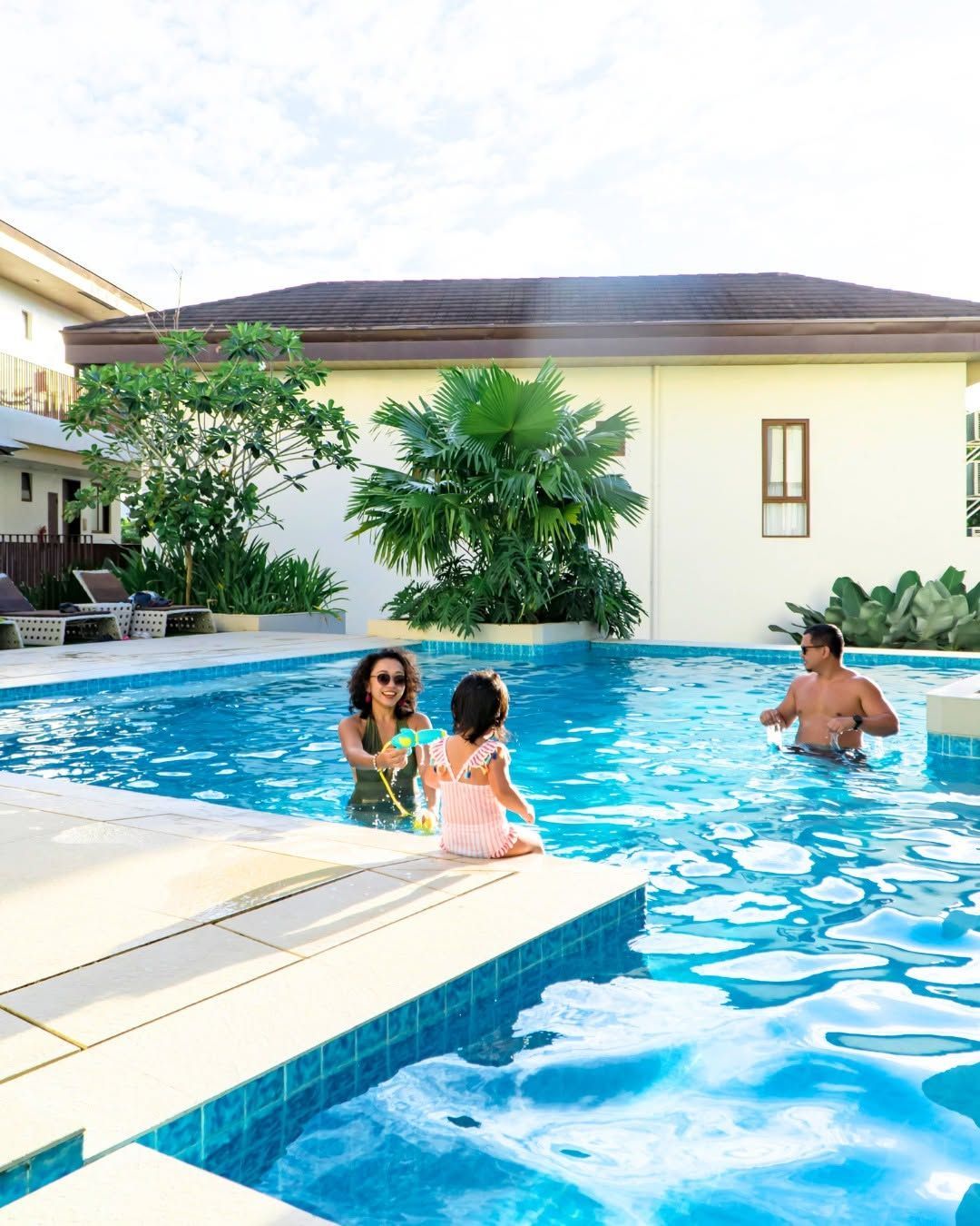 Family with a young child swimming together in the outdoor pool at Charlie's El Nido