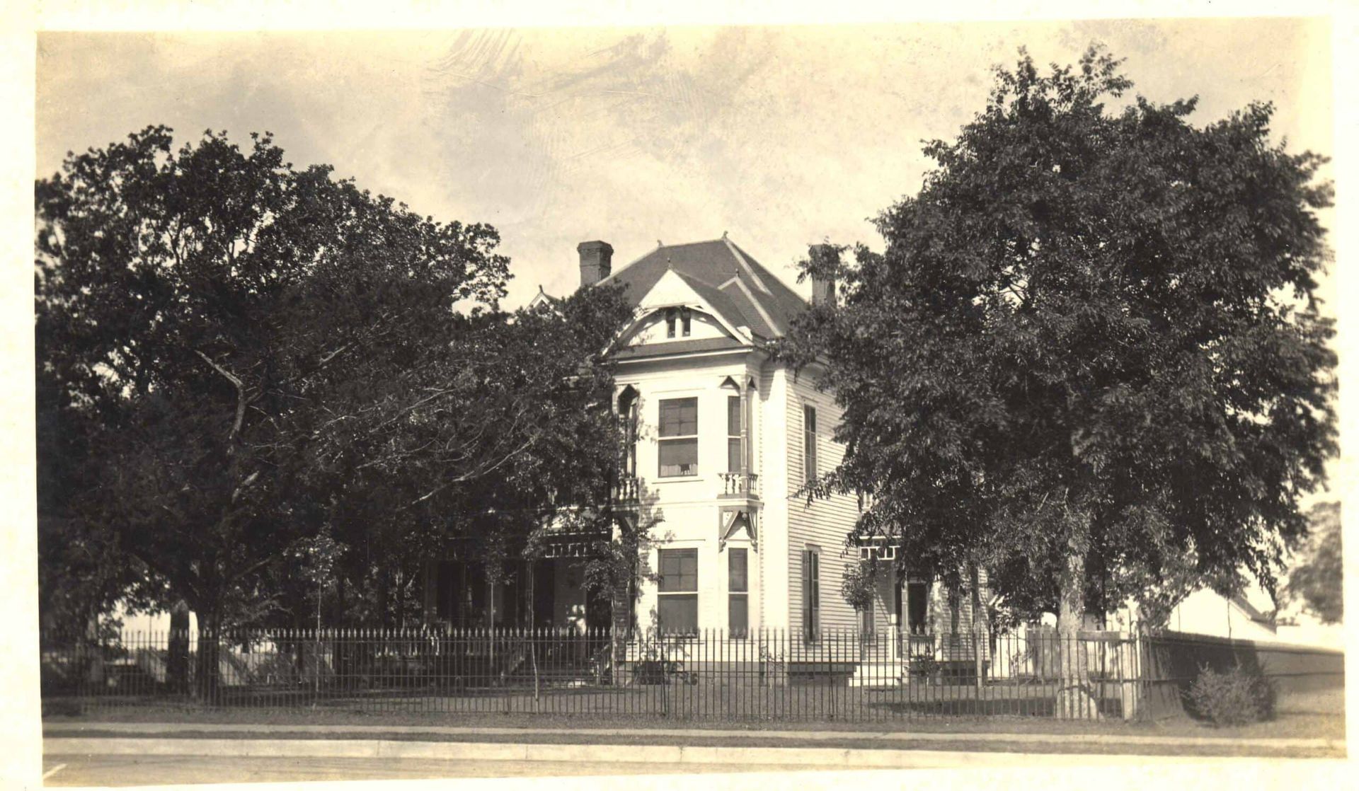 A black and white photo of a house surrounded by trees