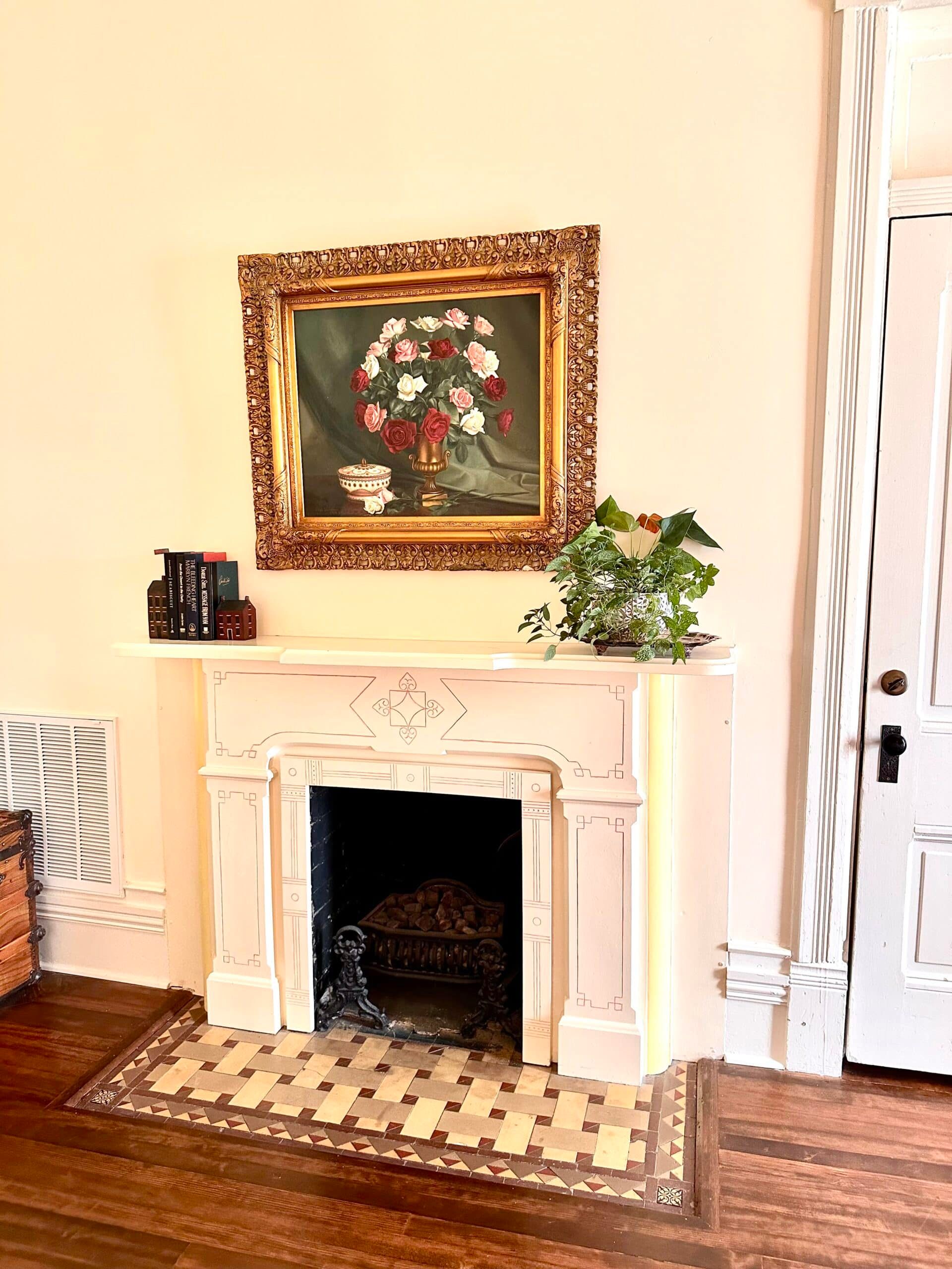 A living room with a fireplace and a painting on the wall above it.