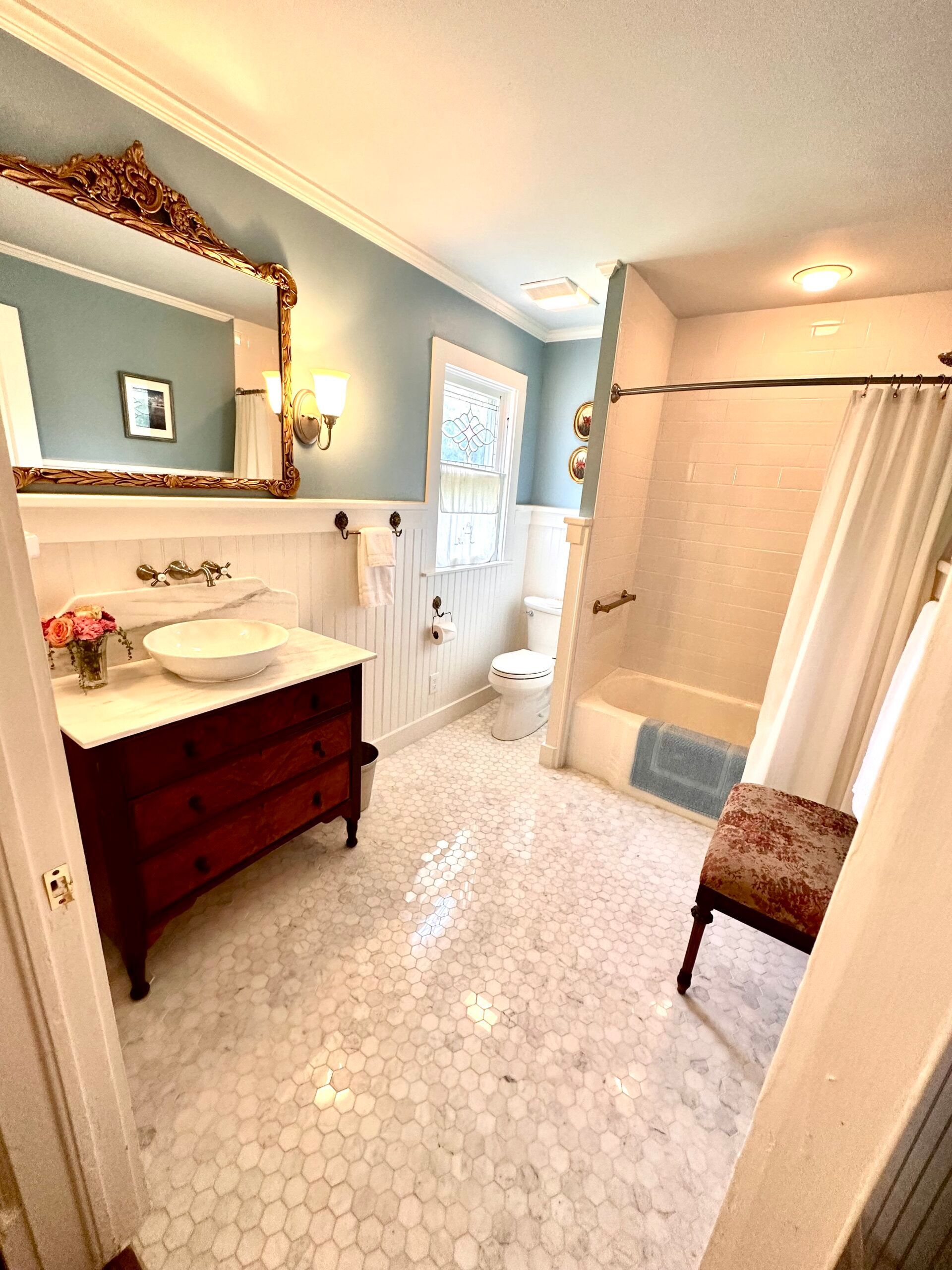 A bathroom with a sink , toilet , shower and mirror.