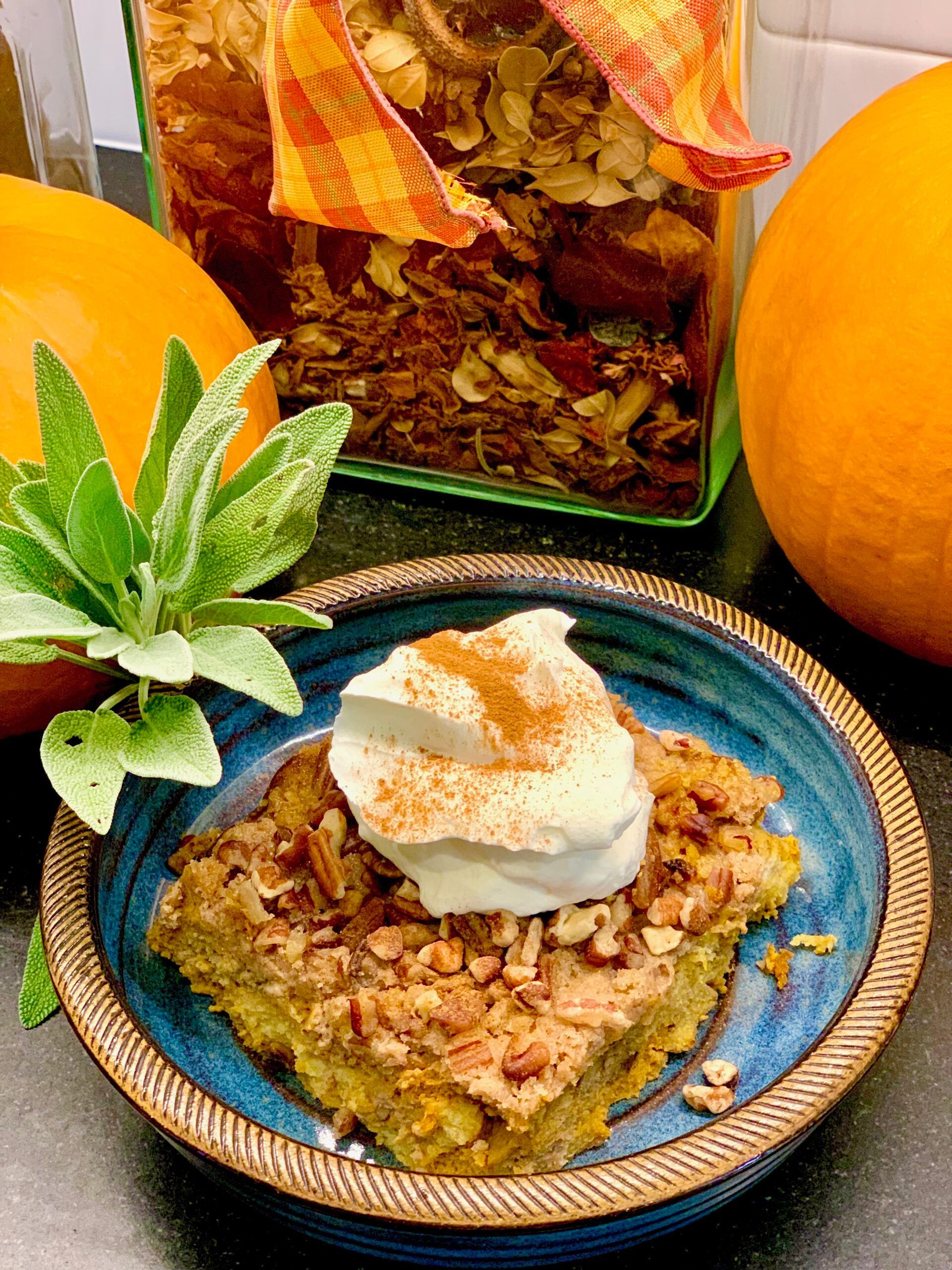 A blue plate topped with a piece of pumpkin pie with whipped cream and cinnamon.