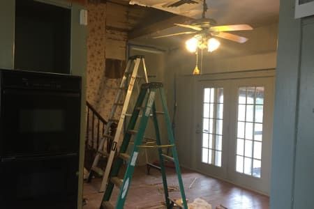A ladder is sitting in a room next to a ceiling fan.
