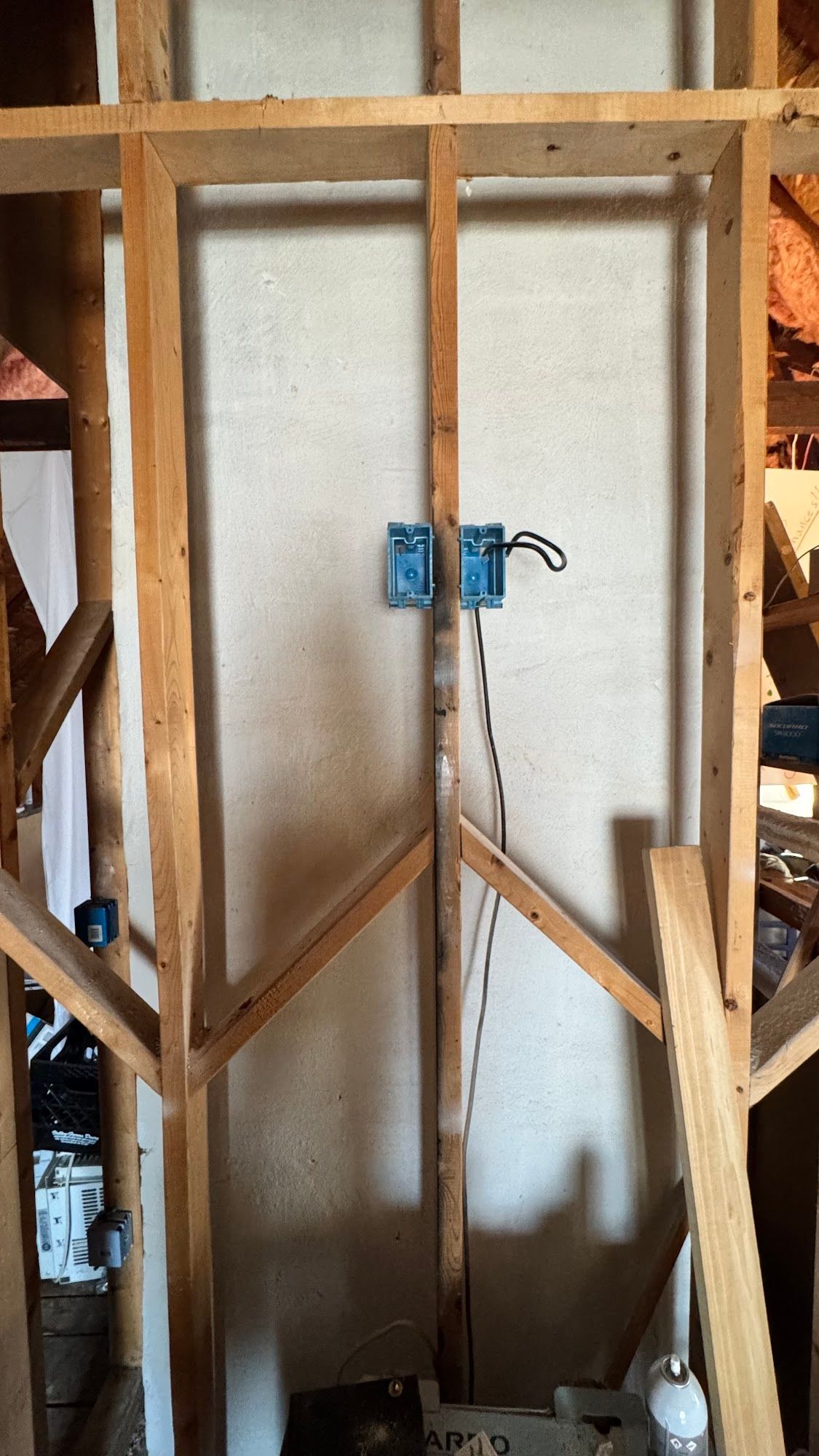 Wooden wall framing with blue electrical boxes.