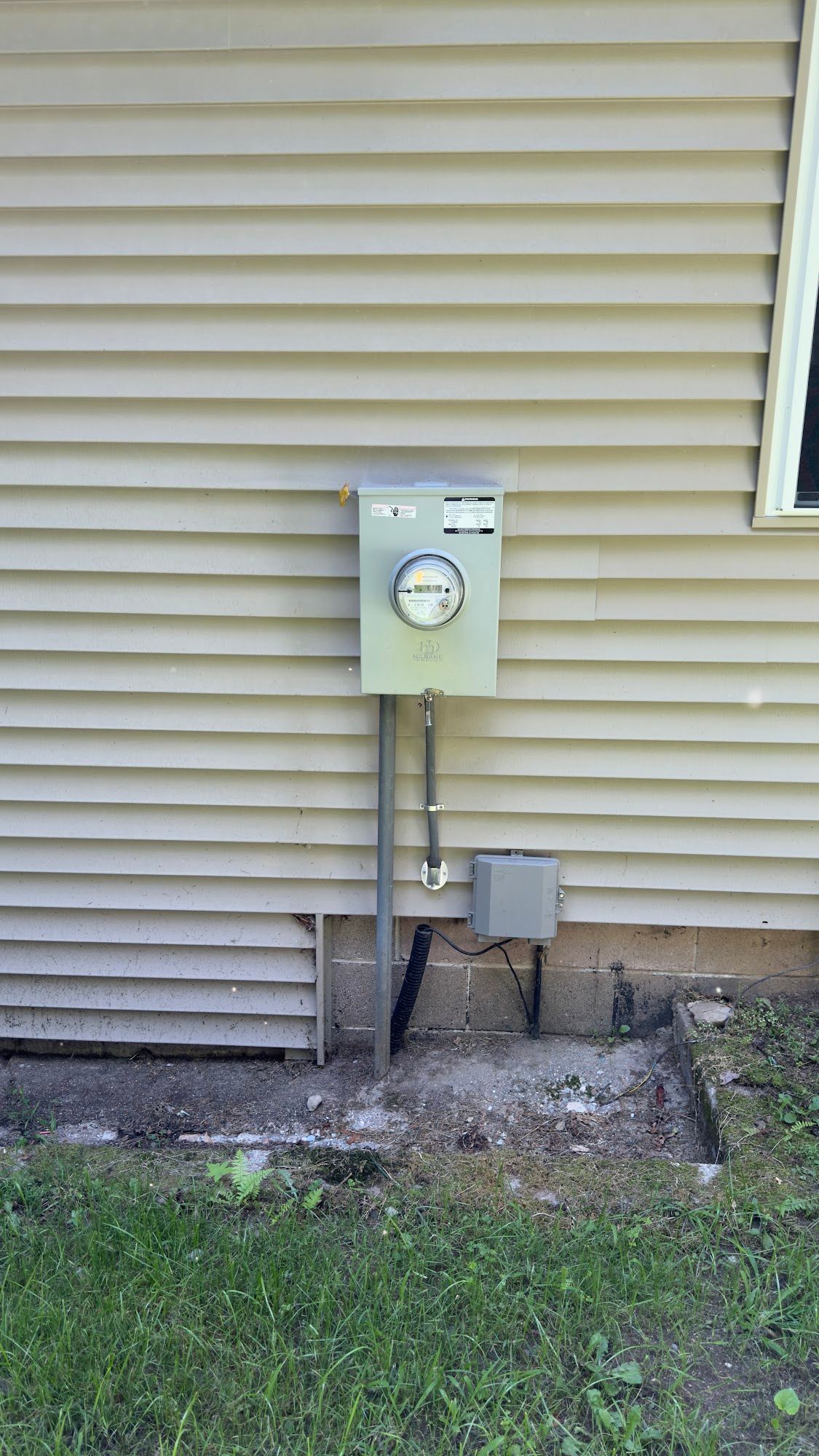 Exterior of a house with a gray electrical meter box mounted on the wall.