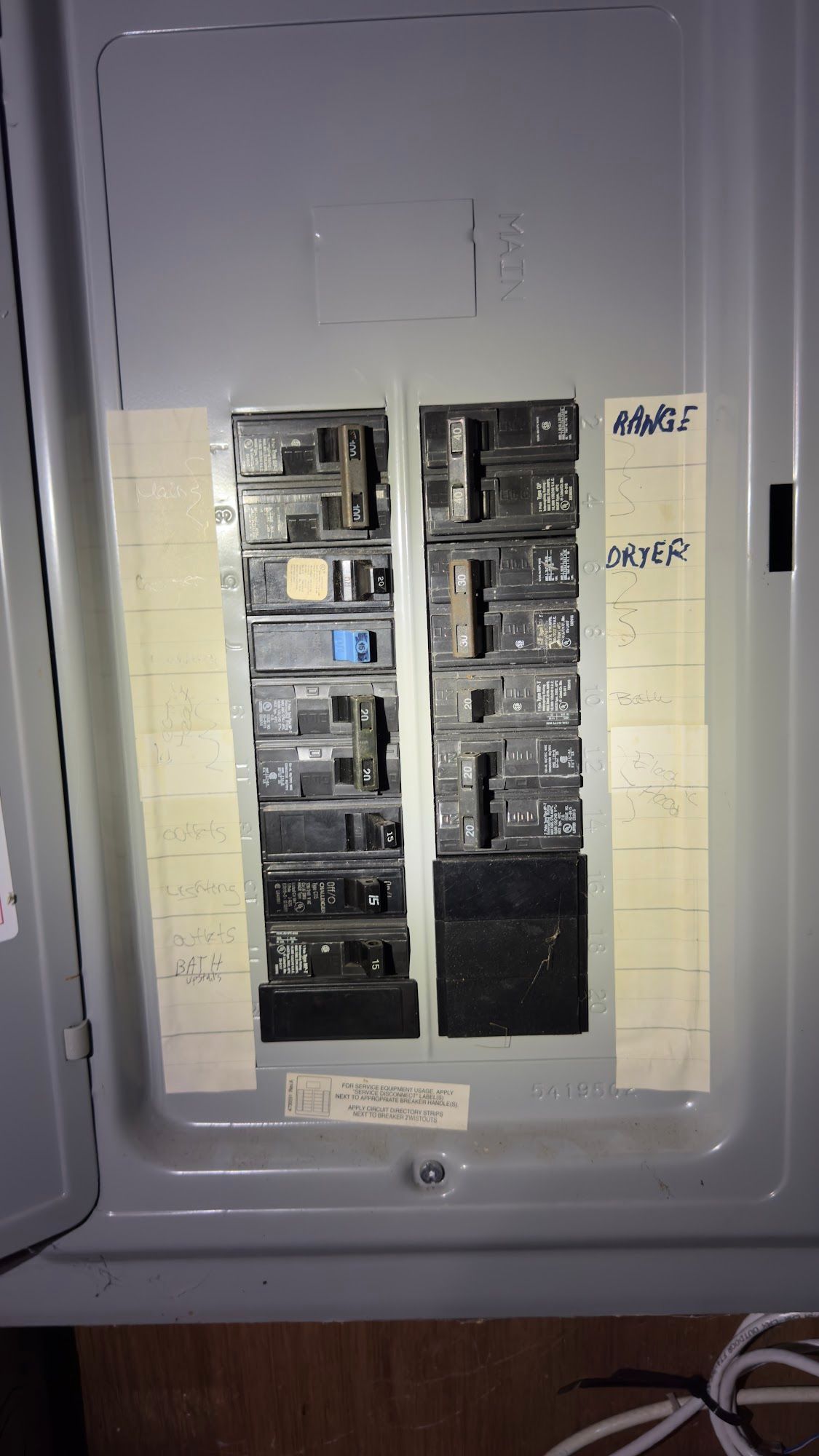 An open electrical breaker panel with multiple switches, labels and a blue switch.
