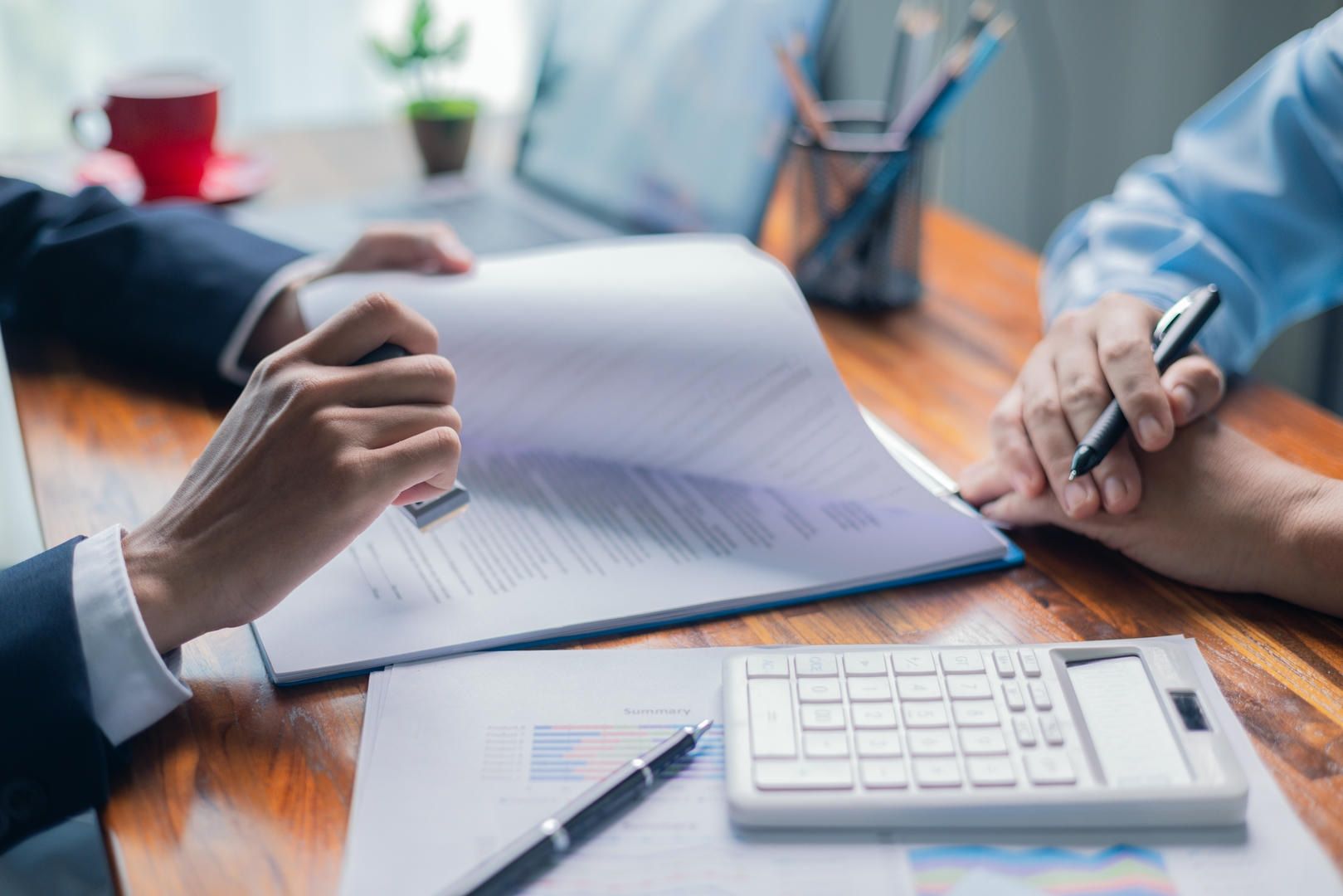 Two people are sitting at a table looking at a piece of paper and a calculator.