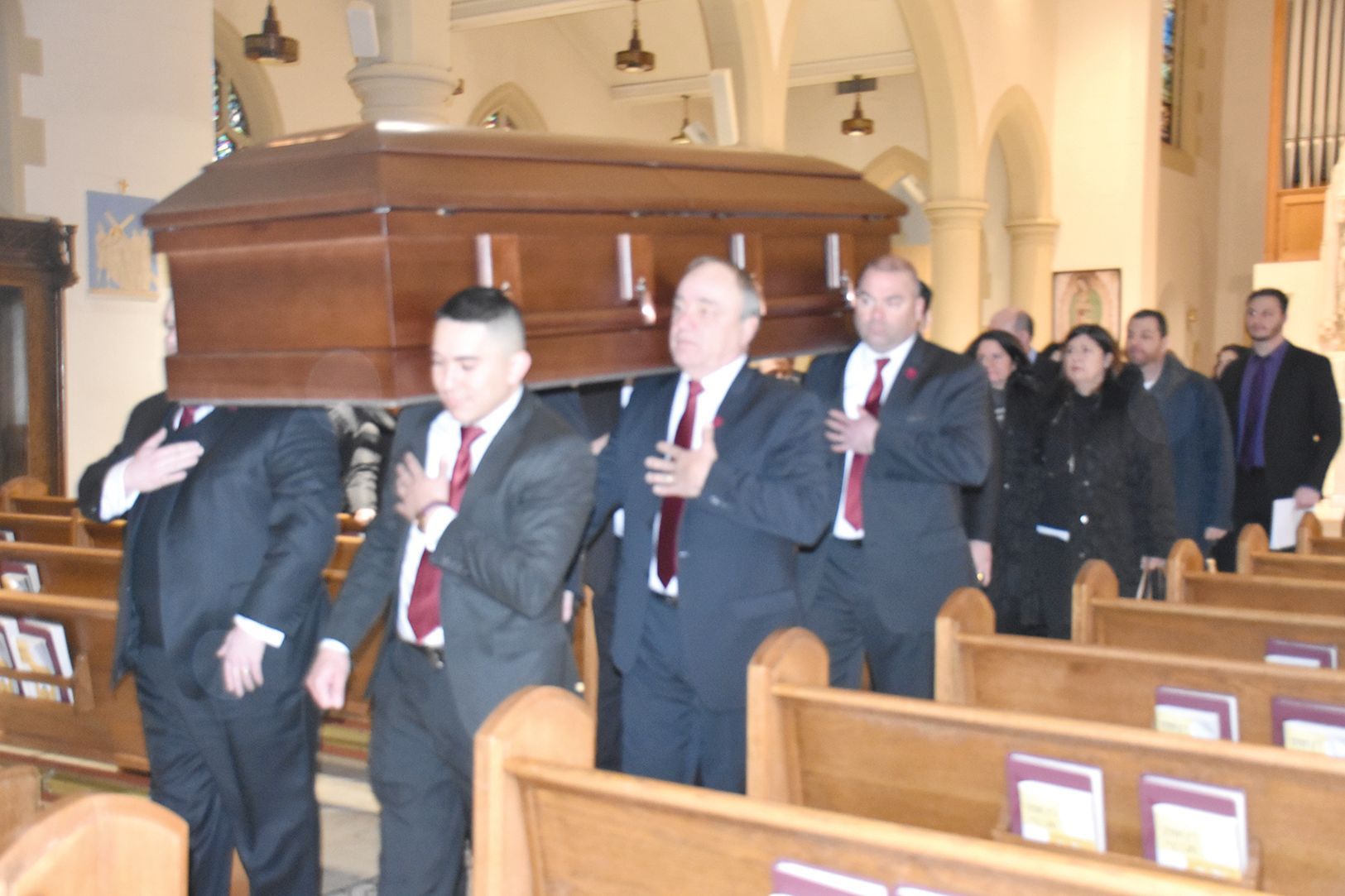 A man in a suit is sitting at a coffin at a funeral.