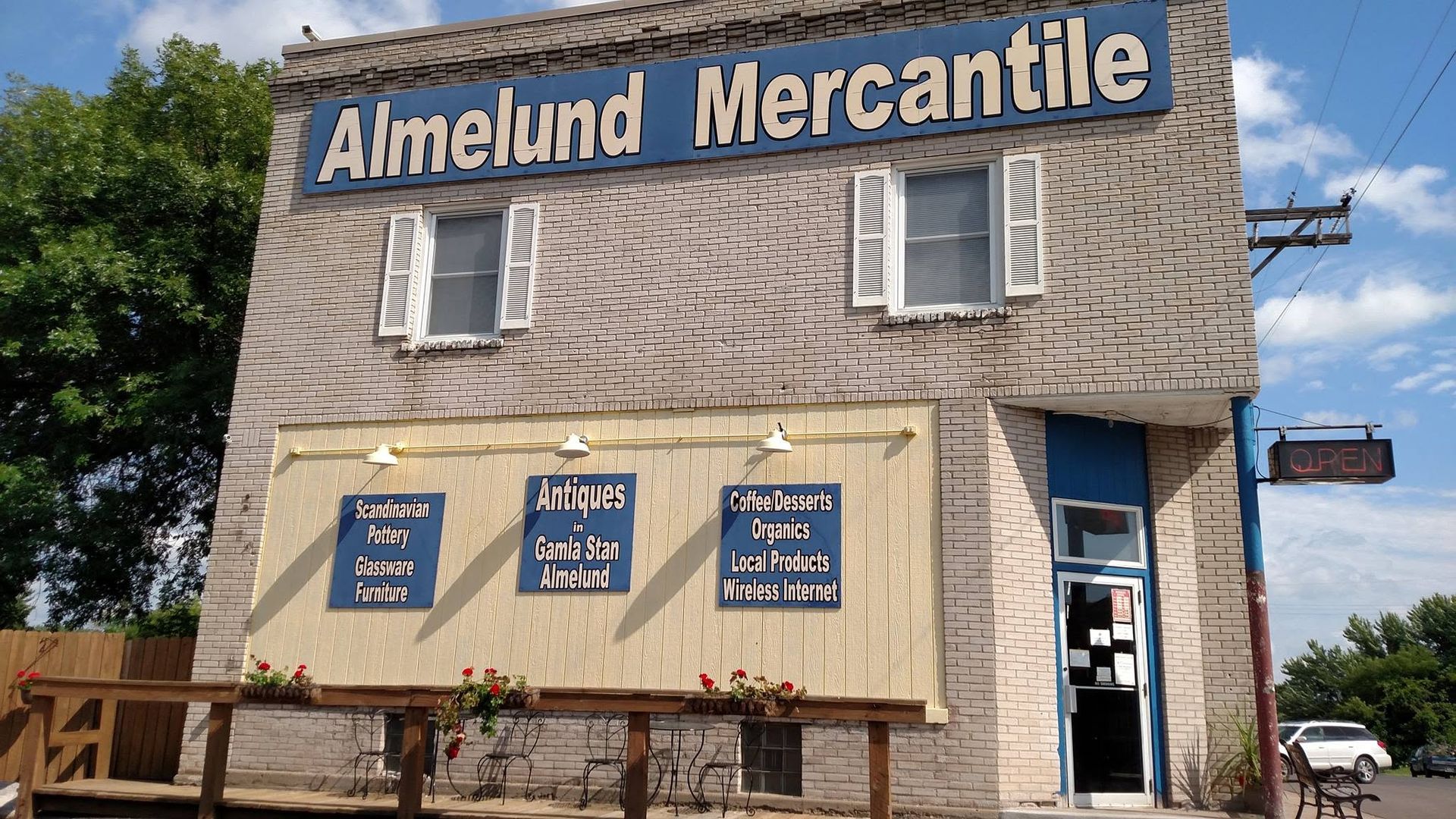 Almelund Mercantile storefront with shingled facade, blue sign, and display windows on a sunny day