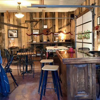 Rustic wooden café interior with stools, tables, and a counter under warm hanging lights