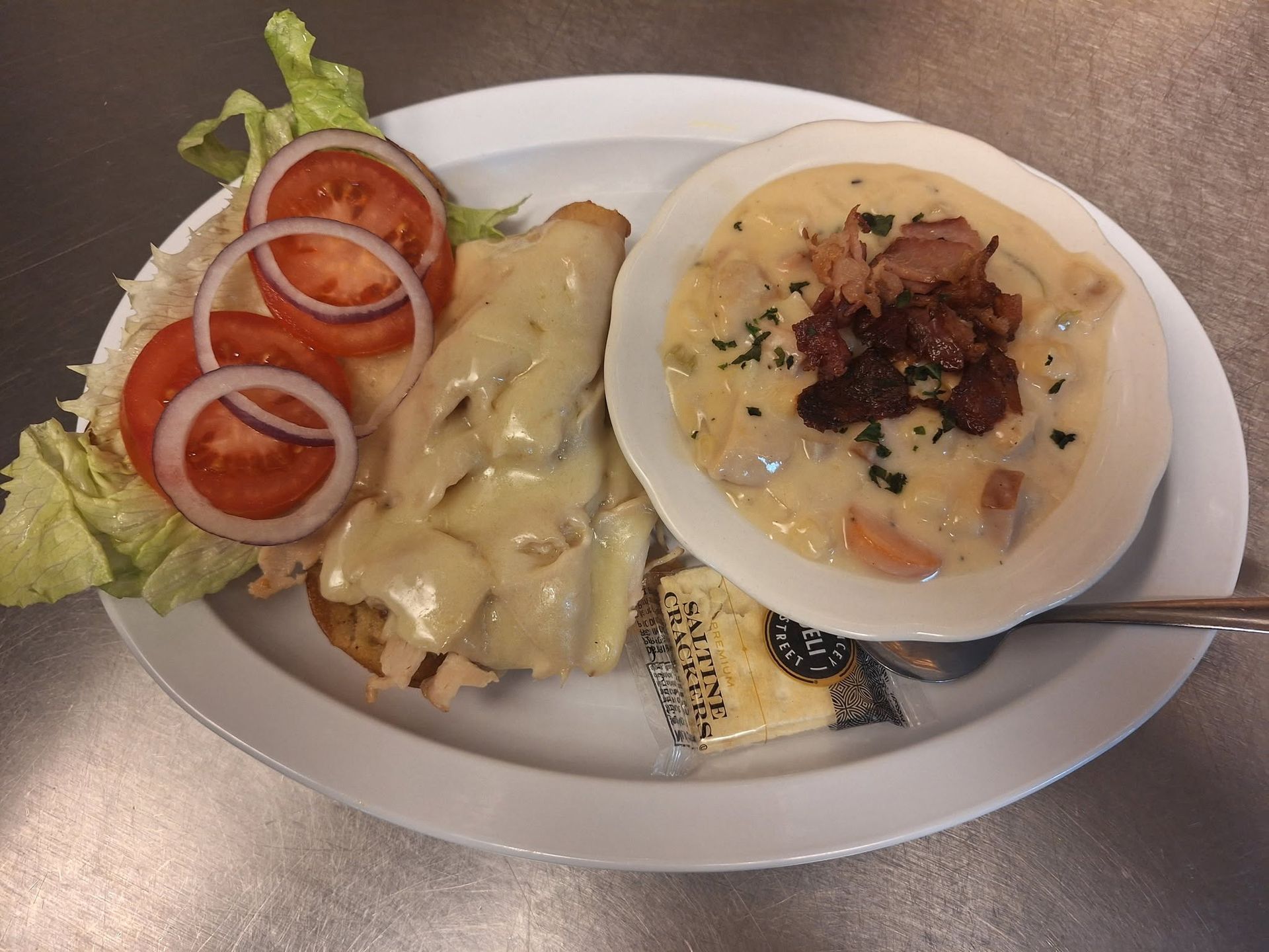 Plate of assorted dishes, including soup, salad, and crepes, on a table with a spoon.