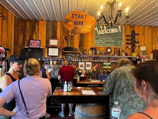 Rustic café counter with people ordering, a “Welcome” sign, and a “Start Here” arrow overhead.