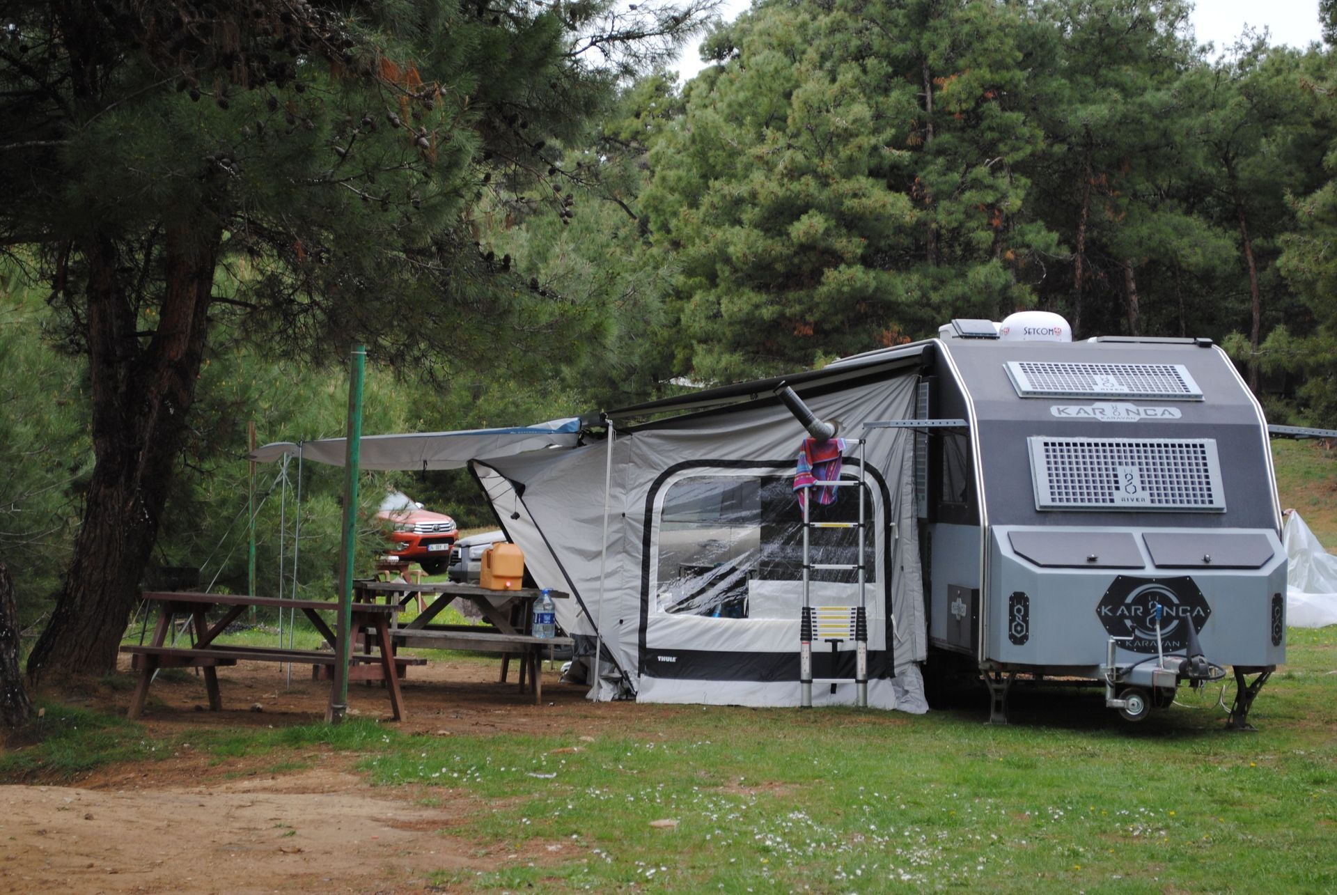 Camper trailer with awning extended in a wooded campsite