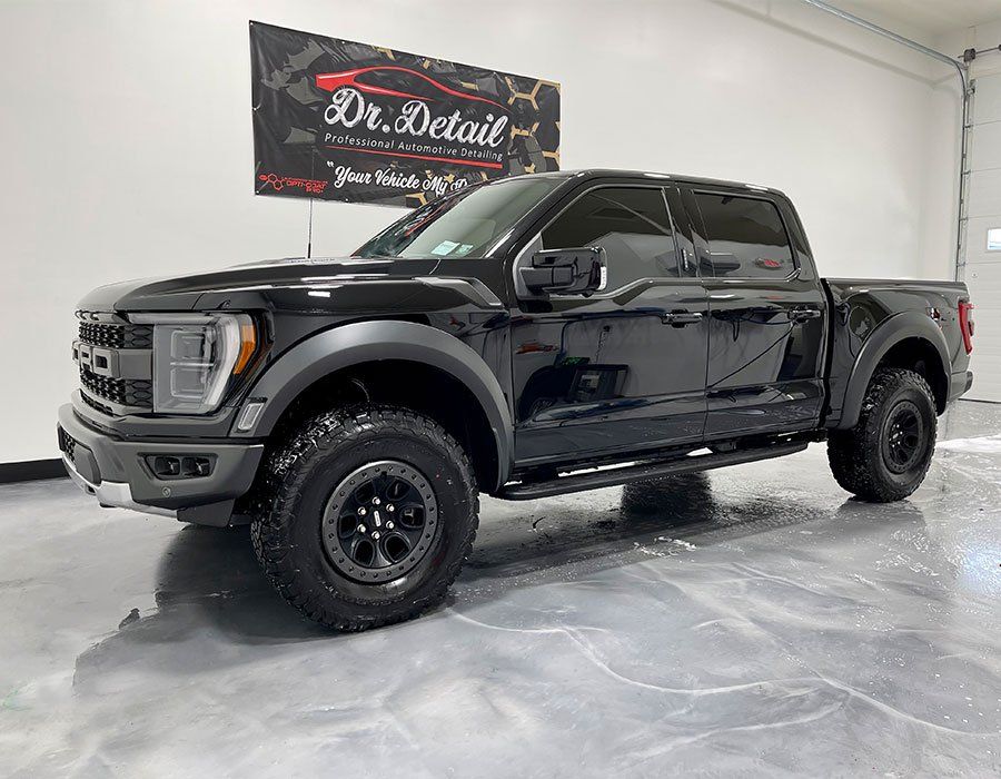 Black Ford Raptor truck inside a detailing shop.