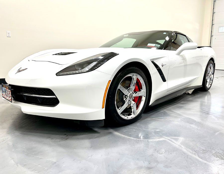 White Corvette sports car parked inside. Red brake calipers visible.
