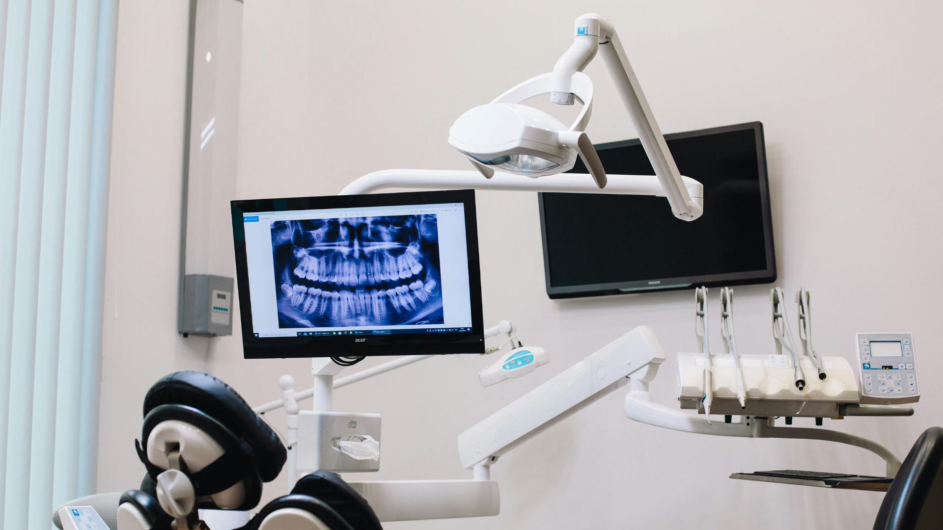 Dental clinic with an X-ray screen, overhead lamp, and dental instruments beside a chair