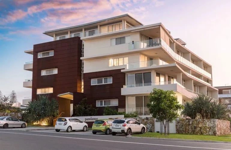 A Large Apartment Building with Cars Parked in Front of It — Nambucca Plumbing in Nambucca Heads, NSW