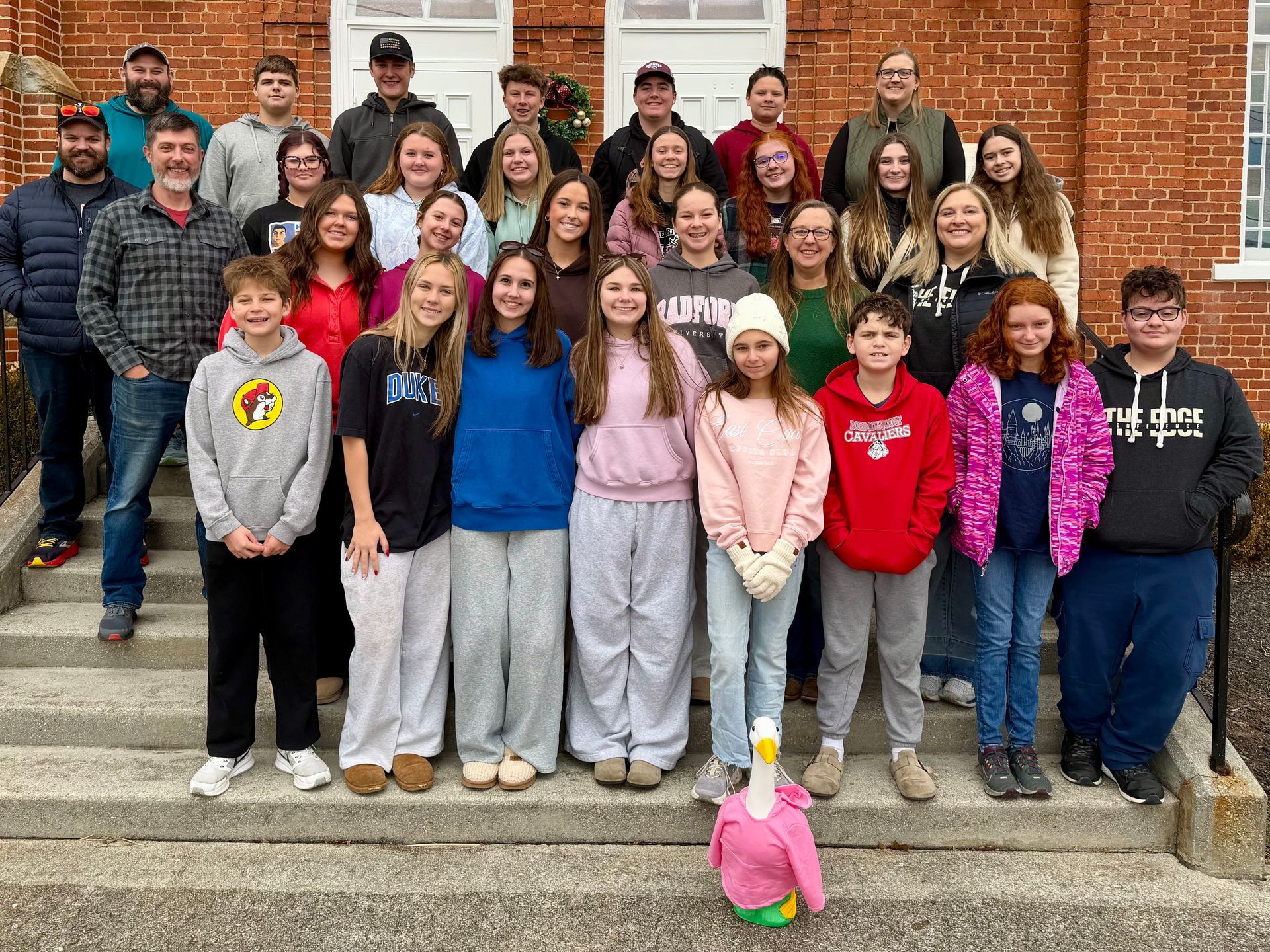 Group of teenagers posing on outdoor steps in front of a brick church.